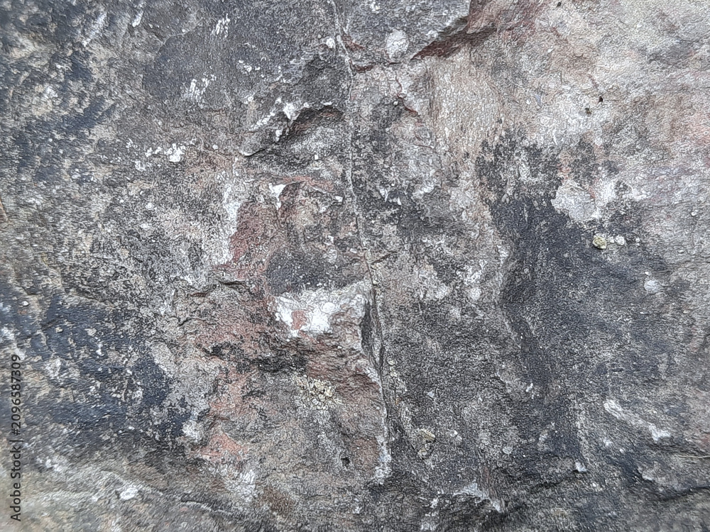 Fototapeta premium Rugged natural stone surface texture with gray black and reddish mineral detail