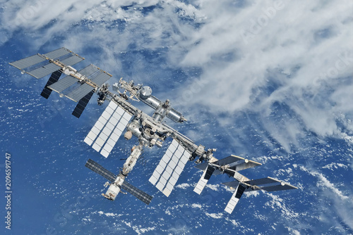International Space Station floats above Earth's blue oceans and white clouds. Elements of this image furnished by NASA
