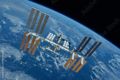 International Space Station floats above Earth's blue oceans and white clouds. Elements of this image furnished by NASA