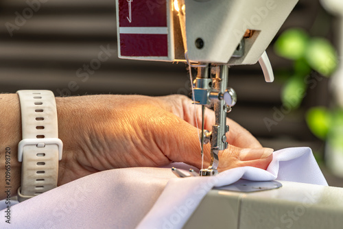 Woman Sewing White Sunshade for Garden Pergola on Sewing Machine