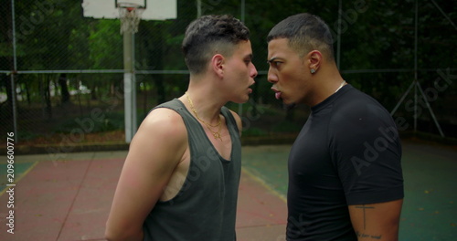 Fotografía Two Hispanic men face off in intense standoff during street basketball game, hea