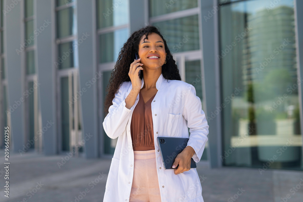 Fototapeta premium Professional doctor talking on phone holding tablet