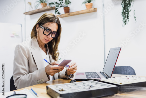 Foto latina geologist woman studying minerals and taking photo with app and using phone at office