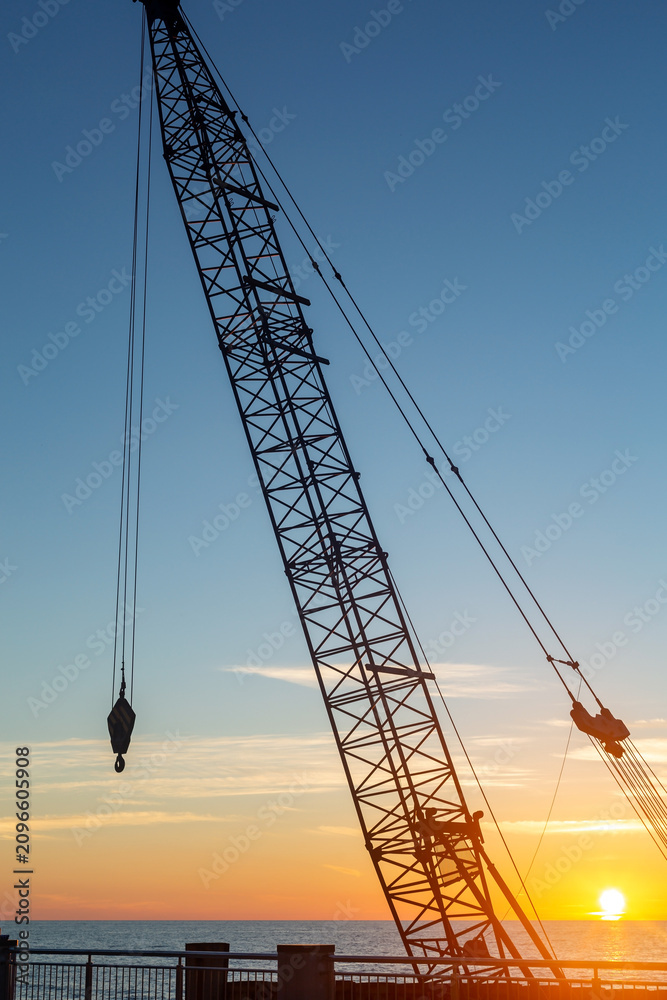Fototapeta premium Crane silhouette against sunset over the Baltic Sea in Svetlogorsk