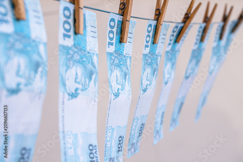 Schilderij op canvas Money laundering concept featuring Brazilian banknotes hanging on a clothesline; corruption, financial scandal, theft