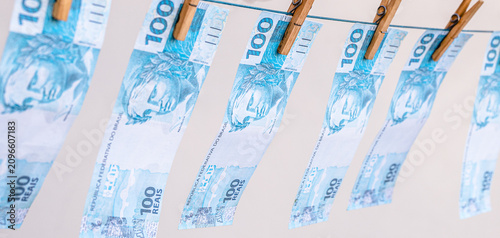 Fotografie Money laundering concept featuring Brazilian banknotes hanging on a clothesline; corruption, financial scandal, theft