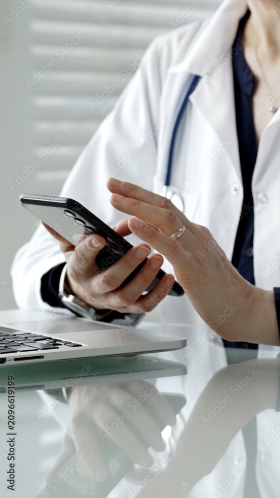 Fototapeta premium Medical professional using smartphone and laptop, checking health data, consulting information, and managing patient records with healthcare technology