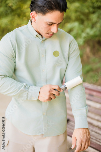 Konstfotografi Young man cleaning shirt with a lint roller