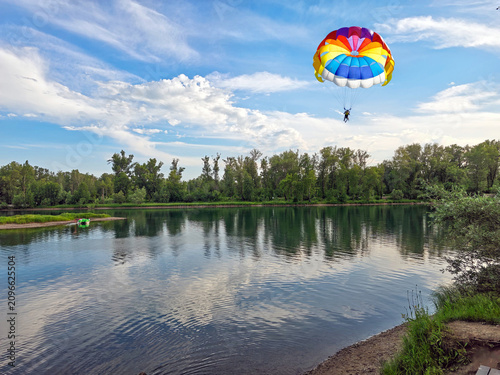 Paragliding behind a motorboat (parasailing) over a body of water.