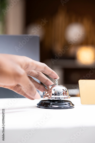 Fotografie Close-up of Black tourist uses service bell to ring for assistance at front desk, check-in process upon arrival in hotel lobby while calling for hotel concierge services in the hospitality industry