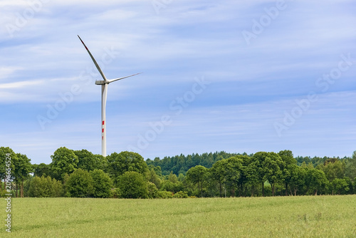 Wind turbine above a green rural landscape with copy space