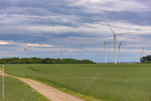 Wind turbines over a green field beneath dramatic clouds