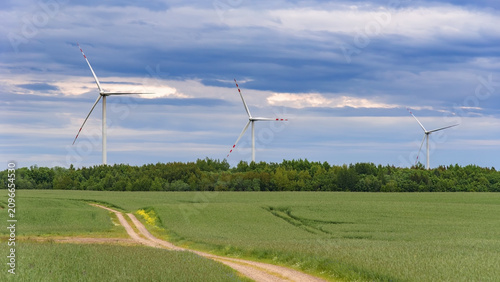 Wind turbines above rural fields under dramatic clouds