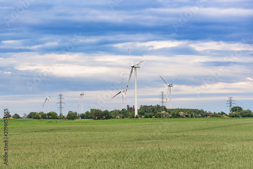 Wind farm and power lines beneath a dramatic cloudy sky