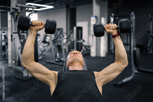 Konstfotografi Muscular man performing incline dumbbell chest press in gym