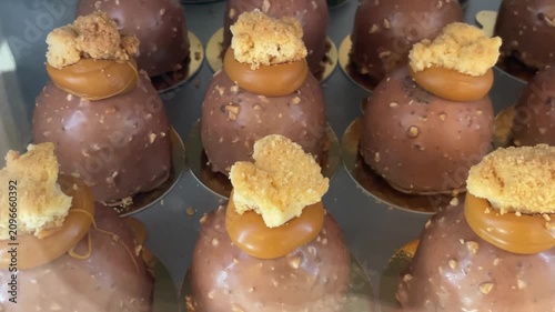 Sweet desserts and pastries are displayed behind a glass showcase in a bakery or cafe arranged for presentation and sale. Retail dessert display. Culinary and gastronomy.