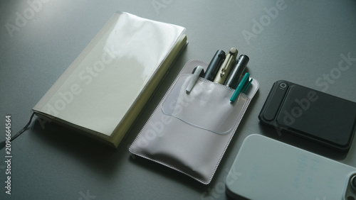 Fotografie Diagonal Overhead Flat Lay of Notebook Pen Pouch and Portable Battery on Gray Ba