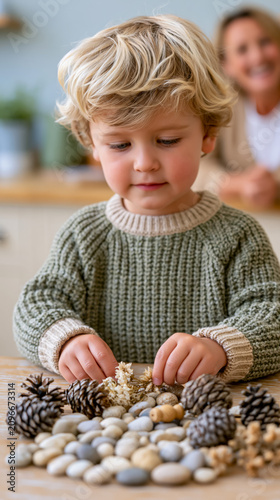 Blonde caucasian child playing with pinecones and rocks indoors