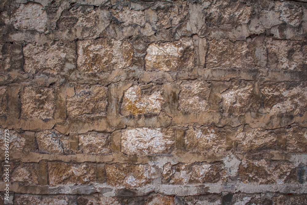 Fototapeta premium Textured stone wall surface with rustic brown blocks and aged mortar for architectural background