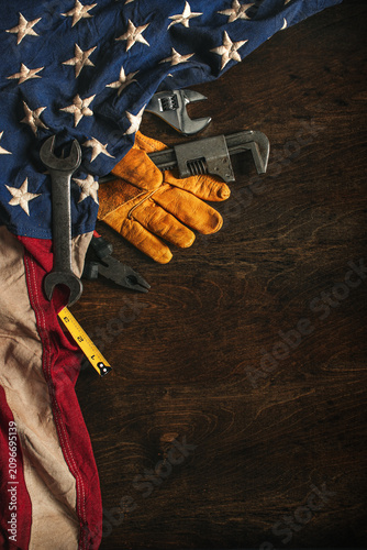 Work glove with tools and American flag on wood background. Symbolic of blue collar workers, USA manufacturing, pride in products Made in United States of America, or Father's day or US Labor Day.
