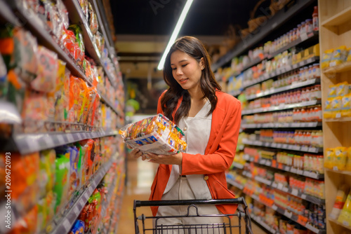 Woman selecting instant noodles in supermarket aisle