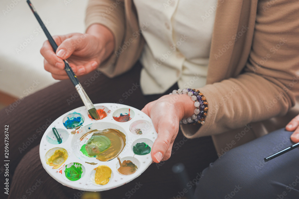Obraz premium A senior hold a palette full of colourful paint in a light, airy home studio, at home, full of love, together, indoors, every day, with a smile, in the morning.