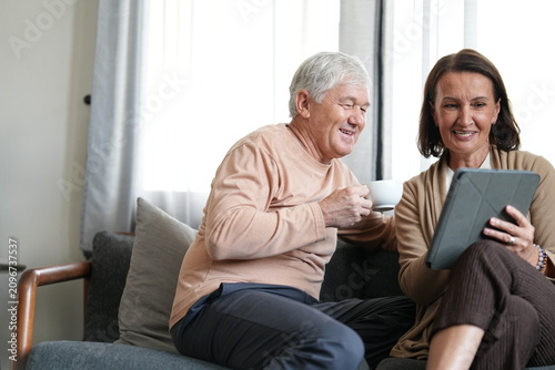 Cuadro en lienzo A loving elderly couple chat over coffee at home in a cosy, sunlit lounge, capturing happy family bonding and quality time, a heartwarming moment of togetherness at home