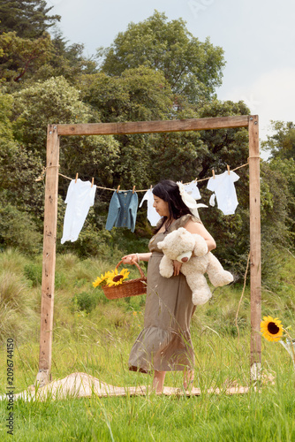 Full Shot of Pregnant Hispanic Woman Standing with Teddy Bear and Sunflower Basket