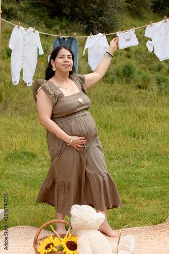 Full Shot of Pregnant Hispanic Woman Holding Baby Beanie on Clothesline