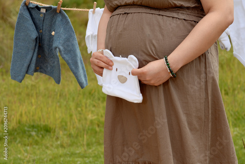 Close Up of Pregnant Hispanic Woman Holding Baby Beanie in Front of Belly