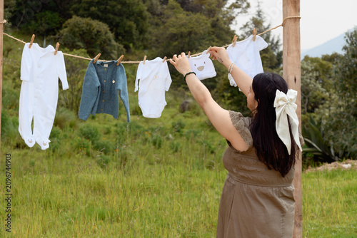 Medium Shot of Pregnant Woman Hanging Baby Clothes Outdoors