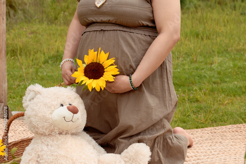 Close Up of Pregnant Hispanic Woman Holding Sunflower in Front of Belly