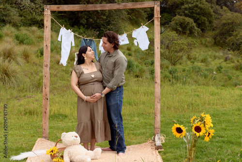 Full Shot of Pregnant Hispanic Couple Embracing in Meadow Setup