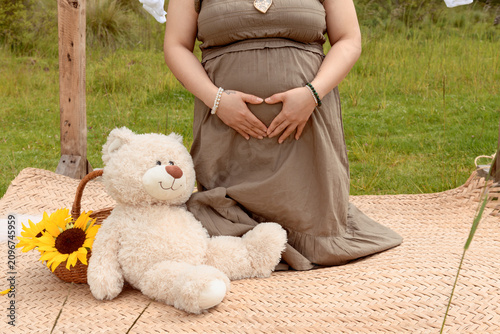 Close Up of Pregnant Hispanic Woman Making Heart Shape with Hands on Belly