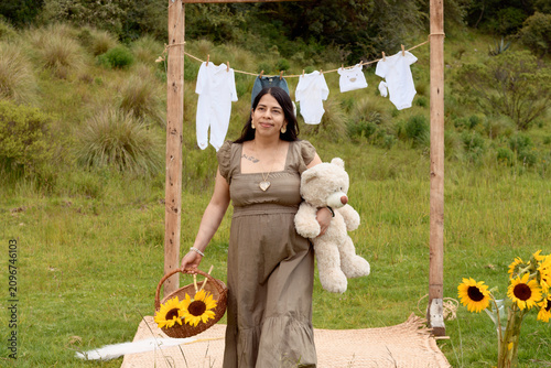 Full Shot of Pregnant Hispanic Woman Standing with Teddy Bear and Sunflower Basket