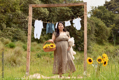 Full Shot of Pregnant Hispanic Woman Standing with Teddy Bear and Sunflower Basket