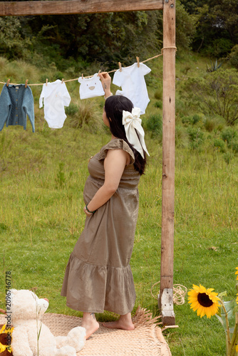 Full Shot of Pregnant Hispanic Woman Touching Baby Clothes on Line