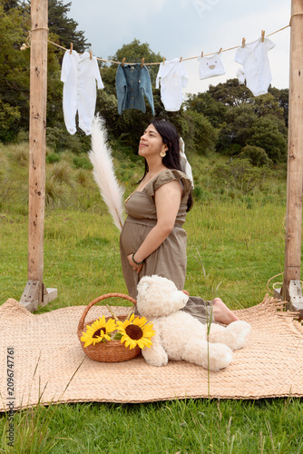 Full Shot of Pregnant Hispanic Woman Kneeling holding Pampas Grass in Meadow Setup
