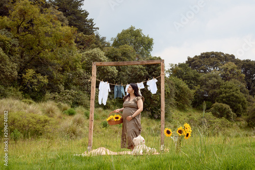 Full Shot of Pregnant Hispanic Woman Standing with Teddy Bear and Sunflower Basket