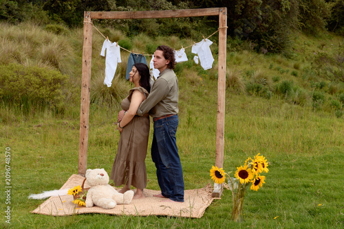 Full Shot of Pregnant Hispanic Couple Embracing in Meadow Setup
