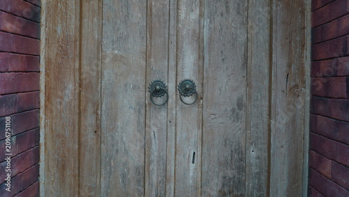 Fotografie Vintage Javanese Wooden Door with Antique Iron Knockers and Red Brick Walls