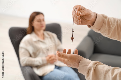 Canvastavla Male psychologists hands with pendulum hypnotizing woman in office, closeup