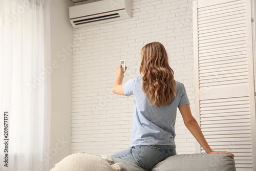 Young woman turning on air ...