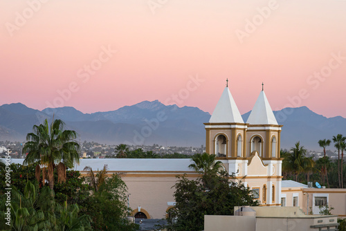 bell towers of mission san jose church and mountains on horizon overlooking city of san jose del cabo mexico