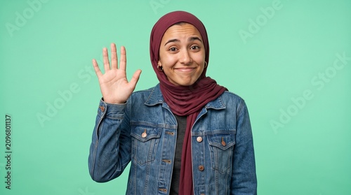 Young woman wearing hijab waving hand in greeting with non verbal greeting friendly headscarf positive portrait background expression lifestyle beautiful cheerful cultural
