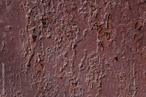 Violet textured background with rust and paint cracks. Reddish-brown base. Raised patches of paint. The aged surface of the steel sheet. Natural shadows