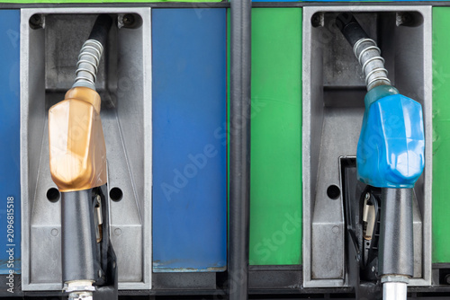 Bild auf Leinwand Close-up of two fuel nozzles, one beige, one blue, inside pump stations
