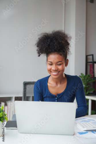 Smiling black woman working on laptop in office