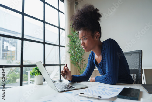 Young businesswoman analyzing data with laptop in office