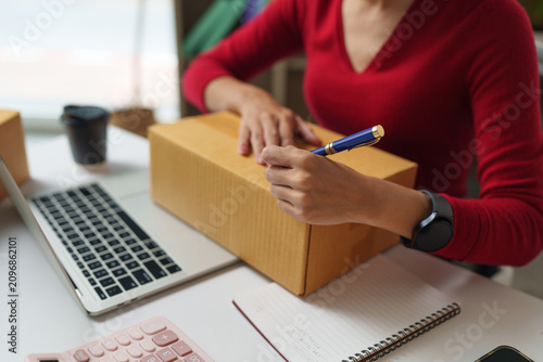 Woman writing on a shipping box for online business delivery